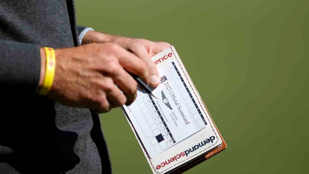 A player is shown filling in a scorecard at the 2023 Genesis Invitational.